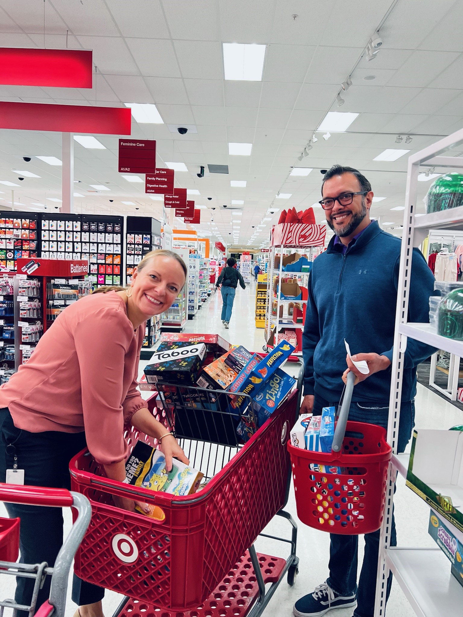 Couple shopping for board games at Target with full shopping cart.